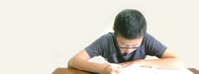 机に向かって勉強中の男子